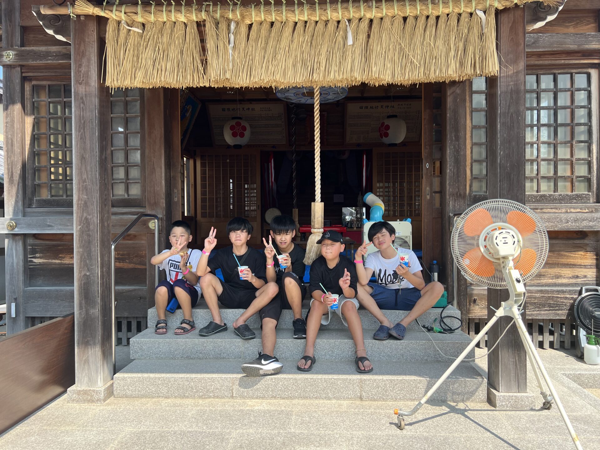 拝殿の階段でかき氷を頬張る子どもたち（福岡市夏祭り・地禄天神社）