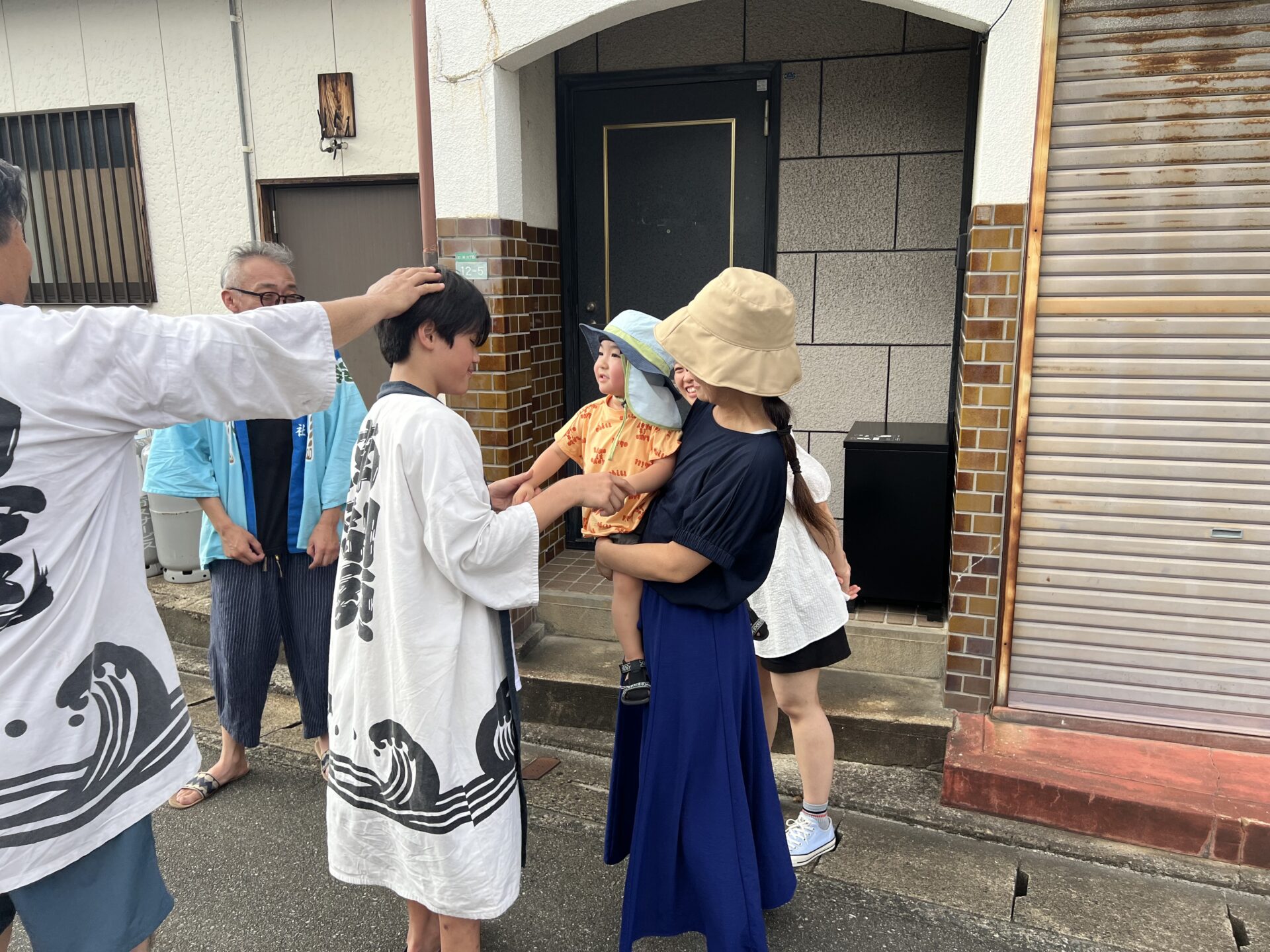 母の腕に抱かれた幼子と目を合わせる小学生