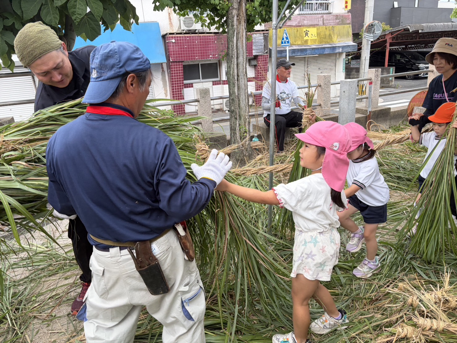 地域の方から盆綱づくりを教わる子ども