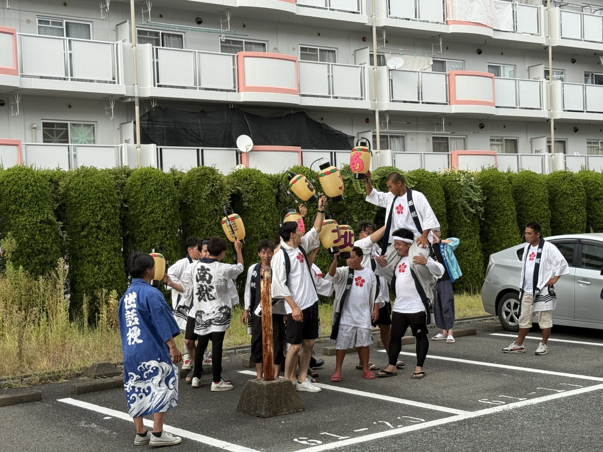 初盆参りの後に大人と若者が提灯を掲げる様子